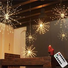 some lights are hanging from the ceiling above a fire place and a remote control is on the table