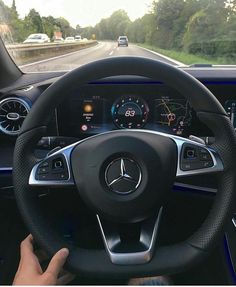 the steering wheel and dashboard of a mercedes benz c - class coupe driving on a country road