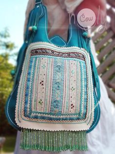 Totally unique one off 100% handmade funky turquoise leather Hmong shoulder bag. This leather bag is made from beautiful turquoise leather and is fantastically designed. The bag has beautiful Hmong hill tribe vintage fabric on the front of it. The hand embroidery is simply amazing. There are also hand painted wooden balls attached to the sides of the bag and beautiful turquoise beads attached to the bottom of the bag. The is closed by a magnetic clip. The bag has a main compartment with a small Blue Tote Hobo Bag For Festivals, Blue Tote Shoulder Bag For Festivals, Bohemian Blue Hobo Tote Bag, Bohemian Pouch Shoulder Bag With Hand-stitched Details, Traditional Blue Shoulder Bag For Everyday Use, Traditional Blue Shoulder Bag For Everyday, Bohemian Blue Shoulder Bag For Festivals, Bohemian Green Leather Bags, Blue Bohemian Satchel For Travel