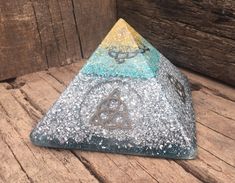 a triangle shaped stone with an celtic symbol on it sitting on a wooden floor next to a wall