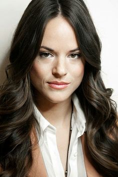 a woman with long dark hair wearing a white shirt