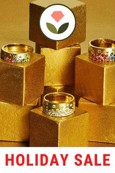 several gold rings are stacked on top of each other in front of a holiday sale sign