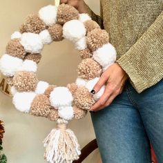 a woman is holding a pom - pom wreath