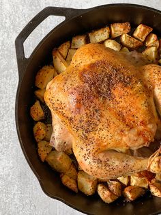 a chicken and potatoes in a skillet with seasoning on the top, ready to be cooked