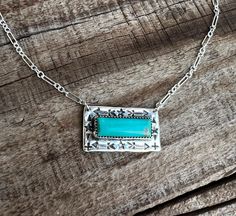 The Kalispel Bar Necklace is a stunning piece of jewelry, perfect for any occasion. This elegant necklace showcases a brilliant 7x20mm genuine turquoise stone at its center, framed by exquisite hand-stamped detailing along the edges. The pendant, measuring approximately 1 inch long by 5/8 inch wide, exudes sophistication and style. It is suspended on a unique 16-inch split cable chain, featuring one long and three short links, with options for a longer chain length available. Ideal for everyday Turquoise Bohemian Necklace With Rectangular Pendant, Bohemian Turquoise Necklace With Rectangular Pendant, Artisan Turquoise Necklace With Rectangular Pendant, Artisan Turquoise Rectangular Pendant Jewelry, Turquoise Gemstone Necklace With Rectangular Pendant, Turquoise Rectangular Pendant Necklace With Gemstone, Turquoise Sterling Silver Rectangular Pendant Necklace, Turquoise Sterling Silver Necklace With Rectangular Pendant, Turquoise Rectangular Pendant Necklace In Sterling Silver