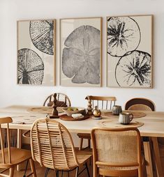 a dining room table with four chairs and three pictures on the wall above it,