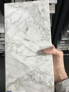 a person holding up a white marble tile