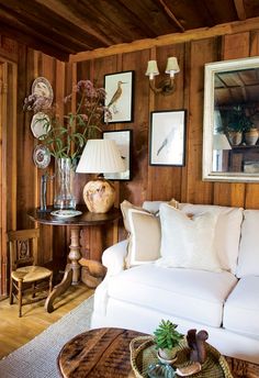 a living room with wood paneling and white couches in front of a coffee table