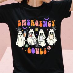 a woman wearing a black t - shirt with three ghostes on it and the words emergency goes