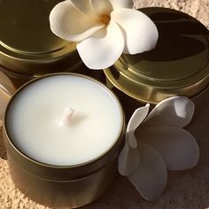 a white flower sitting next to a metal container with a candle in front of it