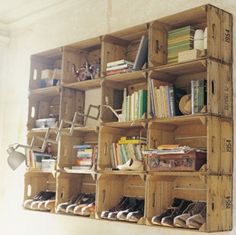 a wooden shelf filled with lots of books on top of a white wall next to a window