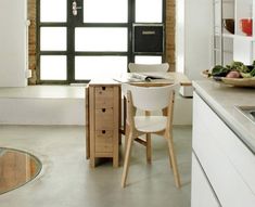 a kitchen with a sink, table and chairs next to a window in the wall