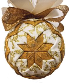 an ornament with gold and white designs on it's side, hanging from a ribbon