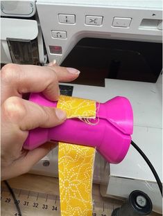 a person is using a sewing machine to sew something yellow and pink on fabric