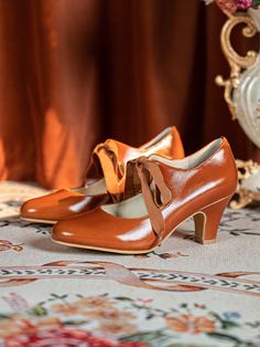 two women's shoes sitting on top of a table next to a vase with flowers