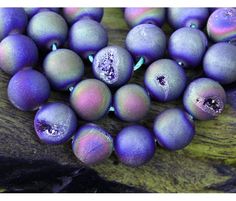 some purple beads are laying on a wooden surface