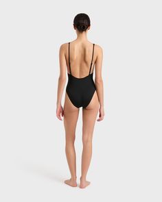 The Juliet One Piece in Black is a timeless and elegant swimsuit featuring a plunge V neckline. Adjustable, shoe-string straps combine with a low cut back to flatter and feature the beauty of the back. Juliet has a medium-high cut leg with regular bottom coverage. Juliet is crafted from our luxury Italian Singuleur® fabric which forms to the body like a second skin. Suitable for bust sizes A-C.Luxury fabric sustainably made in Italy. Sleek Low Back Swimwear For The Beach, Sleek Black Swimwear With Low Back, Sleek Black Low Back Swimwear, Sleek Black Low-back Swimwear, Black Swimwear With Built-in Bra And Low Back, Sleek Backless Swimwear For Summer, Sleek Backless Swimwear, Sleek Low-back Lined Swimwear, Black Low Back Swimwear For Vacation