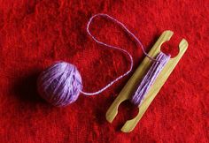 a ball of yarn sitting next to a pair of knitting needles on a red surface