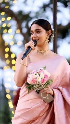 a woman in a pink sari singing into a microphone