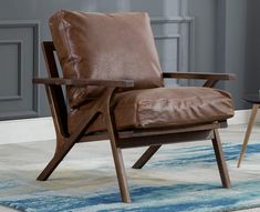 a brown leather chair sitting on top of a blue and white rug in front of a gray wall