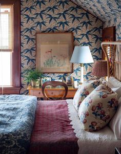 a bed sitting under a window next to a wooden dresser and lamp in a bedroom