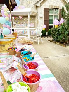 a table with ice cream, strawberries and other desserts on it in front of a house