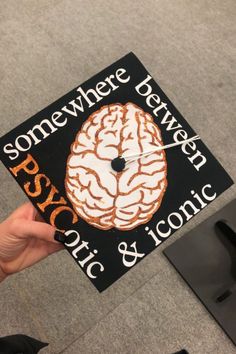 someone is holding up a graduation cap that has a brain on it and the words somewhere between psychic & ironic