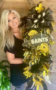 a woman standing next to a wreath with the word saints written on it in gold and black