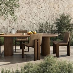 an outdoor table with chairs and fruit on it in front of a stone walled wall