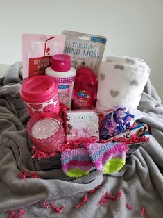 a basket filled with lots of items sitting on top of a gray blanket next to a white wall