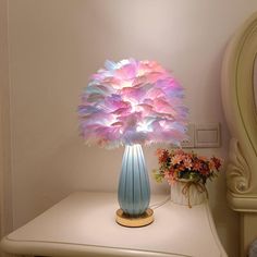 a blue vase filled with pink flowers on top of a white table next to a mirror