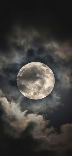 the full moon is seen through dark clouds