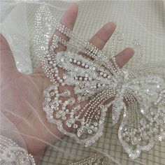 a hand is holding a wedding garter with pearls on it