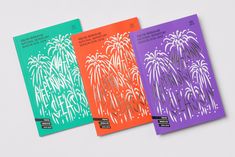 three books with fireworks on them are lined up against a white background and one is purple, the other is green