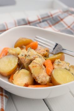 a white bowl filled with potatoes and carrots on top of a checkered table cloth