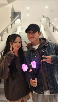 two people standing next to each other in front of an escalator and pointing at the camera