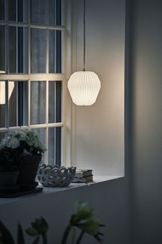 a white light hanging over a window next to a potted plant