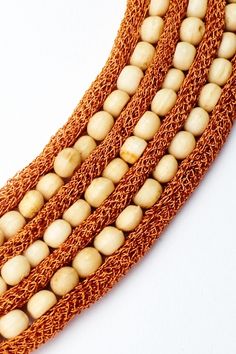 three strands of white beads on an orange string