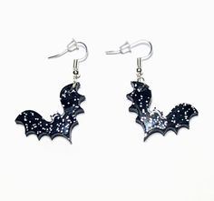 These Small Acrylic Bat Dangle & Drop Earrings in Black Sparkle Glitter are a fun way to keep it spooky while wearing small, lightweight earrings. Each bat is totally unique due to the variations in the silver glitter patterns. Now offering Free Shipping. 🦇This listing is for ONE pair of earrings. 🦇 Each pair is laser-cut and handmade, so slight variations in cut and silver glitter patterns will exist. 🦇 Fish hooks are hypoallergenic Stainless Steel and Nickel-Free  How to Wear these Small Ac Glitter Goth, Whimsical Halloween, Fish Hooks, Goth Punk, Glitter Acrylics, Black Sparkle, Sparkles Glitter, Lightweight Earrings, Light Weight Earrings