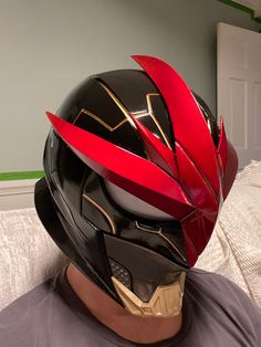 the helmet is red and black with gold details on it's face, as well as an arrow