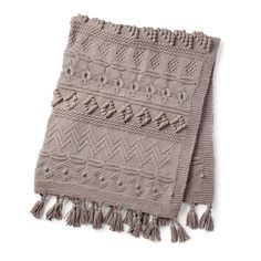 a knitted blanket with fringes on the bottom and an intricate design in grey