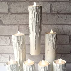 five white candles are sitting in front of a brick wall