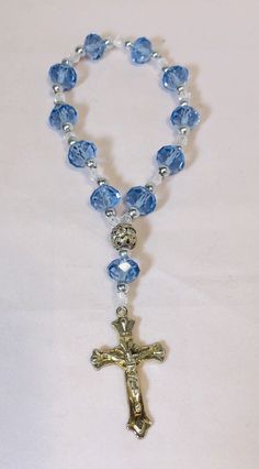 6” Rosary Overflowing Blue-Transparent Multifaceted Glass Beads and Crucifix This beautiful 6-inch bracelet is perfect for any occasion, whether it's Mother's Day, Christmas, birthdays, Valentine's Day, or Confirmation/Communion. The bracelet features 11 stunning blue and multicolored glass beads in a round shape, each measuring .375 inches in width, and one metal bead. The 11 blue beads are multifaceted, adding an extra touch of elegance. The bracelet also has a charming crucifix as a centerpie Rosary Bracelet Diy, Rosary Ideas, Beautiful Rosaries, Catholic Rosary Bracelet, Prayer Jewelry, Mini Rosaries, Chaplet Rosary, Mini Art Journal, Rosary Jewelry