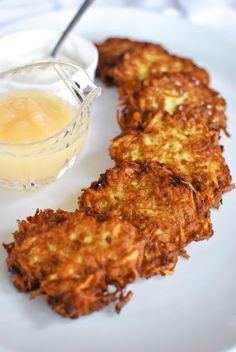 some food is sitting on a white plate with a small bowl of sauce next to it