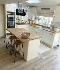 a kitchen with white cabinets and wooden counter tops next to an island in the middle