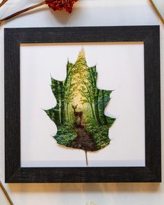 a leaf is hanging on the wall next to a vase with flowers and other items