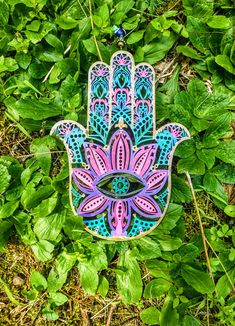 a hamsa hanging on the ground with leaves around it and an eye in the center