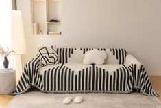 a black and white couch sitting on top of a wooden floor next to a lamp