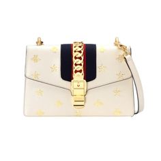 The Gucci Sylvie bag epitomizes luxury and sophistication. Crafted with meticulous attention to detail, this exquisite masterpiece seamlessly blends timeless elegance with a contemporary edge. This gorgeous Gucci Sylvie Bee Top Shoulder Bag features gold-stamped bees and stars, adorned with Gucci's signature web stripe and gold-tone metal chain detail, this bag exudes opulence at every angle.  This shoulder bag can be sported with the matching white leather strap, or with a more festive red, whi High-end Cream Shoulder Bag For Evening, Luxury Everyday Cream Bag, Luxury Gucci Bag With Branded Hardware, Luxury Cream Rectangular Shoulder Bag, Luxury Cream Top Handle Shoulder Bag, Gucci Gold Leather Bag, Classic Gucci Cream Bag, Gold Gucci Leather Bag, Classic Cream Gucci Bags