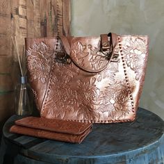 MADE IN MEXICO By: Mexican Artisans Details: Bag Style: Tote Bag Color: Copper Gold 100% Authentic Leather Hand-tooled Floral Design 16" x 11" x 4.5" Handle Straps: 11.5" Drop Closure: Twist Lock Interior: Suede Fabric Flat Bottom Long Leather Wallet: Color: Copper Gold Hand Tooled Floral Design 8" x 4" Closure: Magnetic Snap 1 Zipped Coin Compartment 2 Money Compartments 10 Card Compartments Contact us for more details PLEASE READ BEFORE PURCHASE: Each product is handmade from Mexico causing di Everyday Embossed Tote Satchel, Embossed Tote Bag For Travel, Embossed Satchel Shoulder Bag For Everyday Use, Vintage Embossed Tote Bag, Embossed Double Handle Bag For Daily Use, Daily Use Embossed Satchel Shoulder Bag, Embossed Bags With Double Handle For Daily Use, Daily Use Embossed Bags With Double Handle, Everyday Leather Bag With Engraved Details